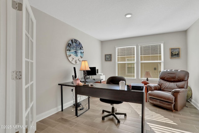 home office with a textured ceiling, wood finish floors, and baseboards