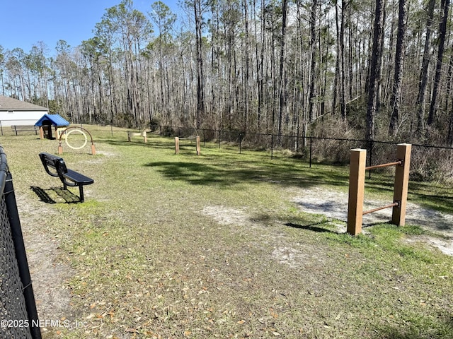 view of home's community featuring fence, a view of trees, and a lawn