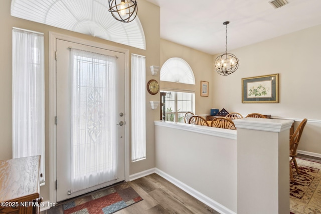 entryway with visible vents, baseboards, a notable chandelier, and wood finished floors