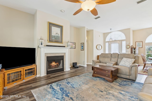 living room with a tile fireplace, visible vents, and wood finished floors