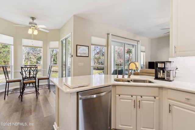 kitchen featuring ceiling fan, a sink, light countertops, stainless steel dishwasher, and decorative backsplash