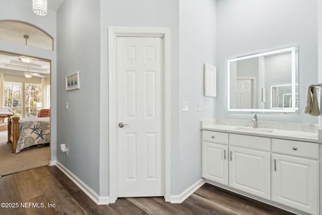 bathroom featuring baseboards, vanity, ensuite bathroom, and wood finished floors