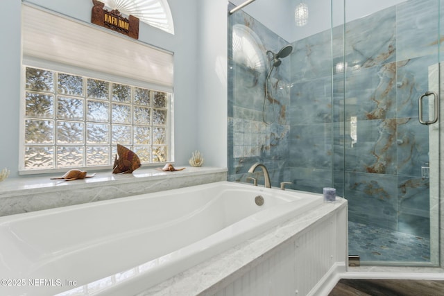 bathroom featuring plenty of natural light, a shower stall, and a bath