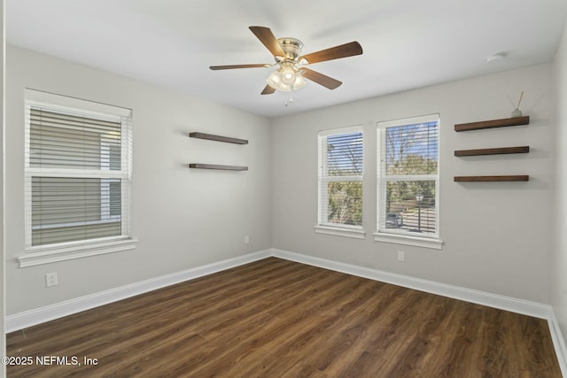 spare room with ceiling fan, dark wood finished floors, and baseboards