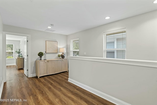 hallway featuring dark wood-style floors, plenty of natural light, baseboards, and recessed lighting