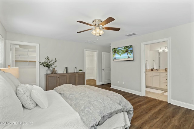 bedroom featuring visible vents, a spacious closet, baseboards, and wood finished floors