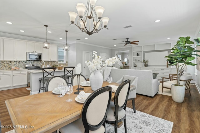 dining area featuring dark wood-style floors, a ceiling fan, visible vents, and crown molding