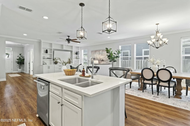 kitchen featuring visible vents, dark wood-style flooring, decorative light fixtures, stainless steel dishwasher, and a sink