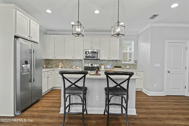 kitchen with ornamental molding, dark wood-style flooring, stainless steel appliances, light countertops, and white cabinetry