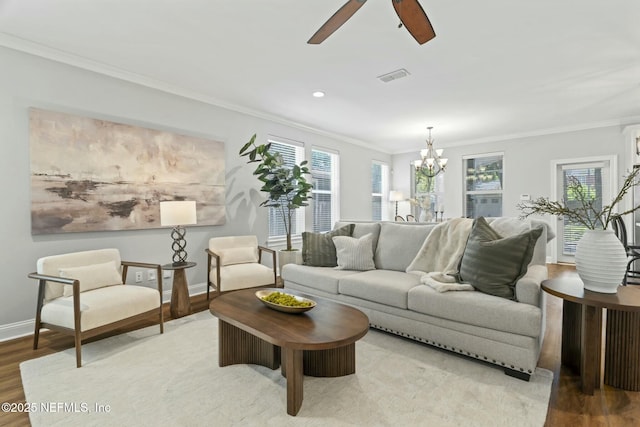 living area featuring a healthy amount of sunlight, crown molding, visible vents, and wood finished floors