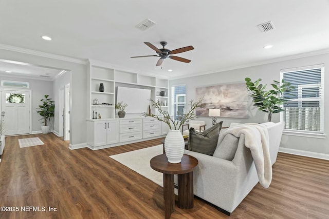 living area with baseboards, visible vents, wood finished floors, and ornamental molding