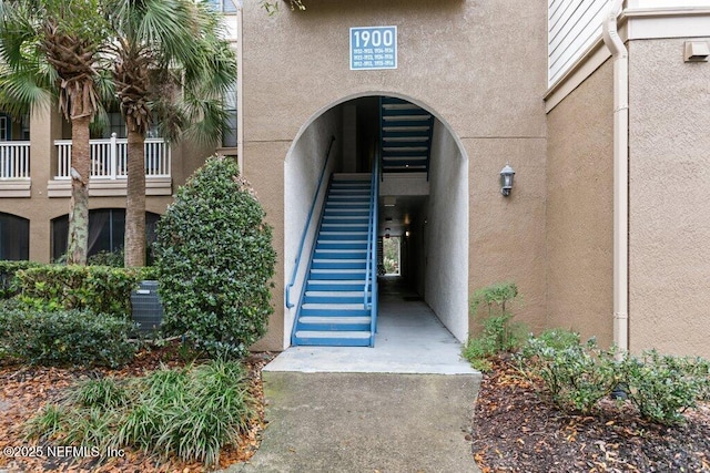 entrance to property with central air condition unit and stucco siding