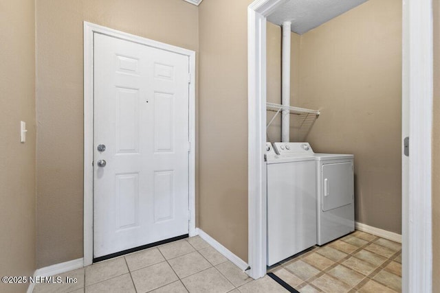 washroom featuring light tile patterned floors, laundry area, independent washer and dryer, and baseboards