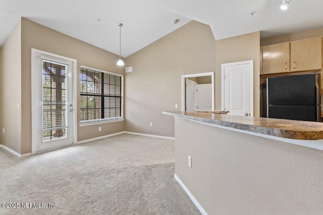 kitchen with light carpet, freestanding refrigerator, hanging light fixtures, light countertops, and light brown cabinetry