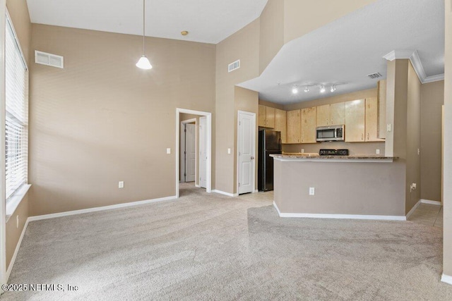 kitchen featuring stainless steel microwave, freestanding refrigerator, a peninsula, light brown cabinetry, and pendant lighting