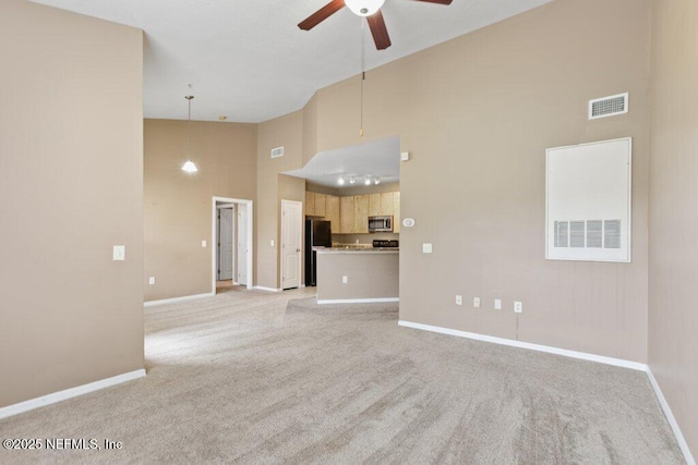 unfurnished living room featuring ceiling fan, high vaulted ceiling, light colored carpet, visible vents, and baseboards