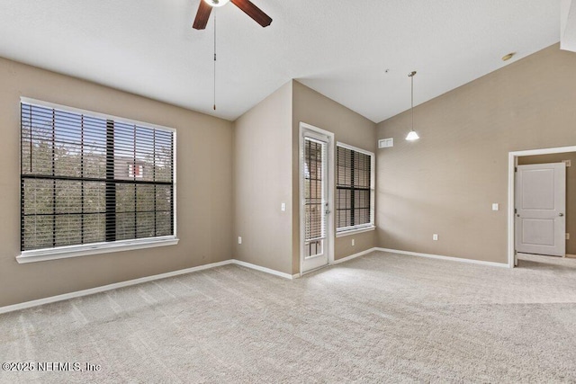 empty room featuring a ceiling fan, light colored carpet, vaulted ceiling, and baseboards