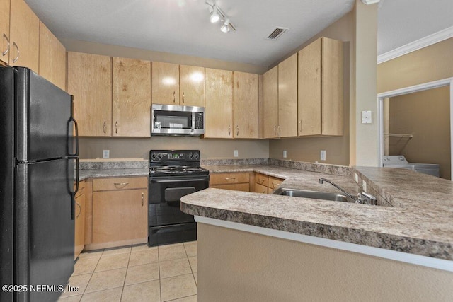 kitchen featuring washer and dryer, light countertops, black appliances, and light brown cabinetry