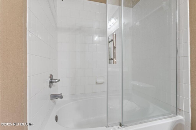 bathroom with enclosed tub / shower combo and a textured wall