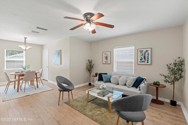 living room featuring light wood-style flooring, visible vents, and baseboards