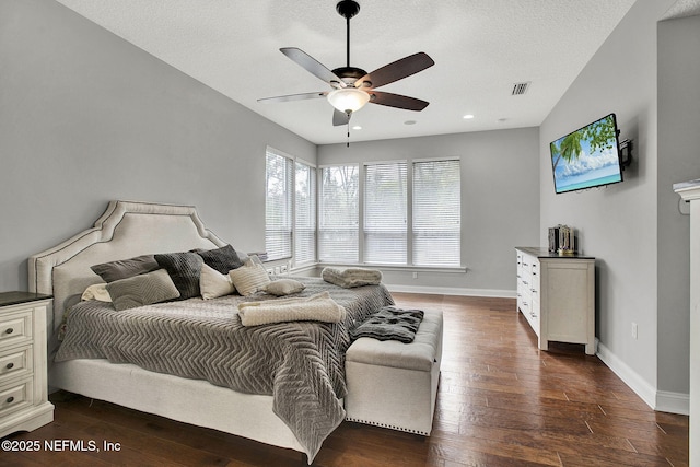 bedroom featuring dark wood-style floors, visible vents, a ceiling fan, a textured ceiling, and baseboards