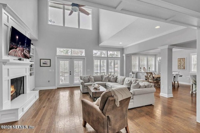 living room featuring a wealth of natural light, a warm lit fireplace, baseboards, and hardwood / wood-style floors