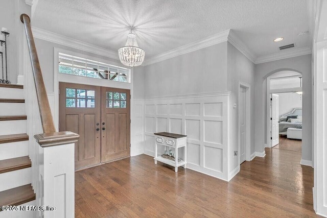 foyer with visible vents, a decorative wall, stairway, and wood finished floors