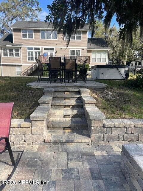 exterior space with a hot tub, stairs, outdoor dining area, and a patio