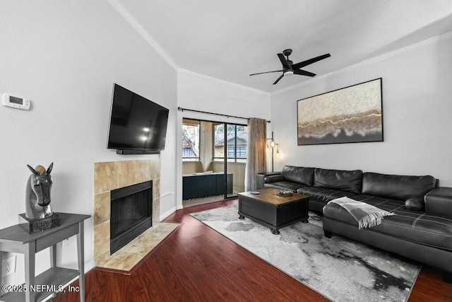 living area with dark wood-style floors, a fireplace, a ceiling fan, and crown molding