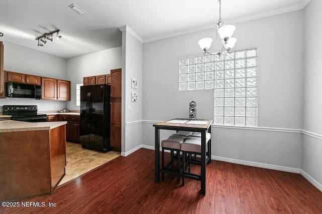 kitchen with dark wood-style flooring, pendant lighting, light countertops, and black appliances