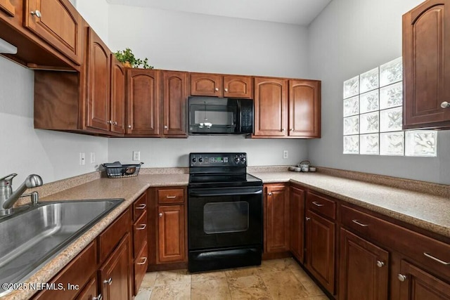 kitchen featuring black appliances, light countertops, and a sink