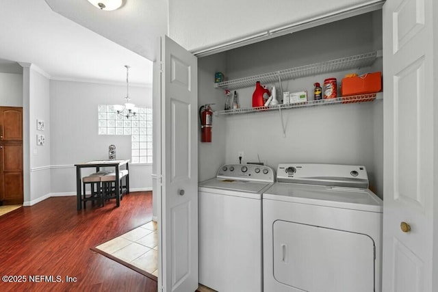 laundry area with a chandelier, laundry area, dark wood-type flooring, baseboards, and washer and dryer