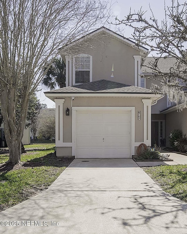 view of front of property with a shingled roof, driveway, an attached garage, and stucco siding