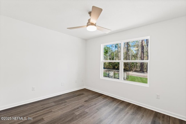 empty room featuring dark wood-style flooring, a ceiling fan, and baseboards