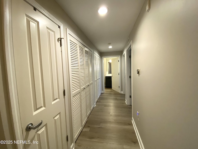 hall with light wood-style floors and baseboards