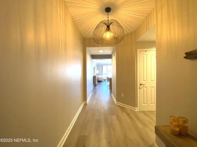 corridor featuring baseboards and wood finished floors