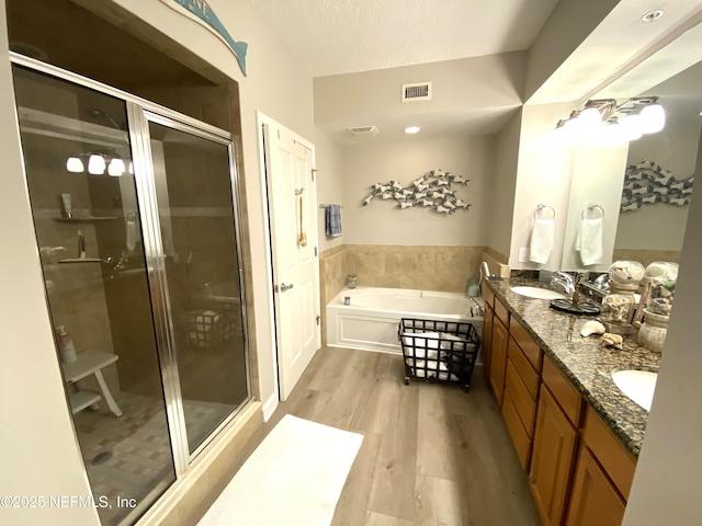 full bath with a bath, wood finished floors, a sink, and visible vents