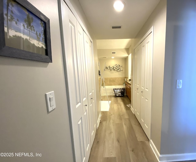 hall with visible vents and light wood finished floors