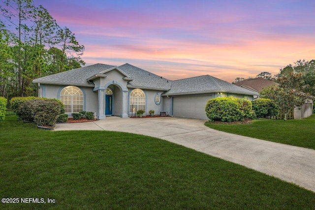 view of front of property with stucco siding, driveway, a front lawn, a shingled roof, and a garage