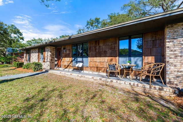 rear view of house featuring a yard and brick siding