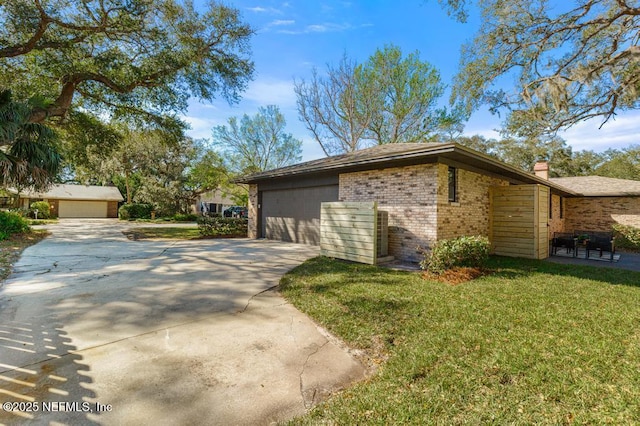 view of home's exterior with a yard, driveway, brick siding, and an attached garage