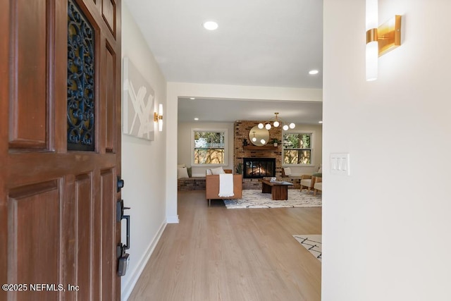 entrance foyer featuring light wood-type flooring, a brick fireplace, baseboards, and recessed lighting