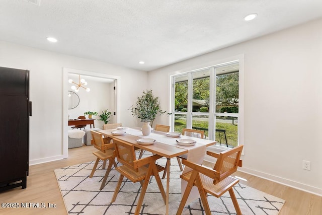 dining space with baseboards, a textured ceiling, light wood-type flooring, a notable chandelier, and recessed lighting