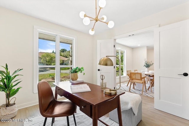 office area featuring baseboards, light wood finished floors, a wealth of natural light, and a notable chandelier