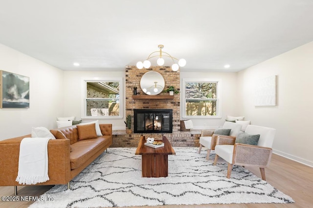 living area featuring recessed lighting, a brick fireplace, wood finished floors, a chandelier, and baseboards