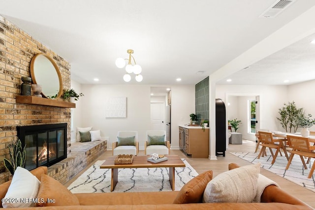 living area featuring a fireplace, light wood finished floors, recessed lighting, visible vents, and baseboards