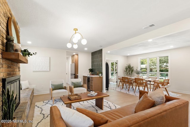 living room featuring baseboards, a fireplace, visible vents, and light wood-style floors