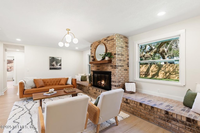 living room with recessed lighting, a notable chandelier, wood finished floors, baseboards, and a brick fireplace