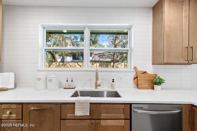 kitchen featuring a sink, light countertops, stainless steel dishwasher, a wealth of natural light, and tasteful backsplash