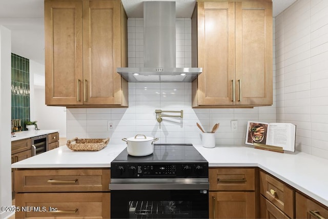 kitchen featuring wall chimney range hood, decorative backsplash, electric stove, and light countertops